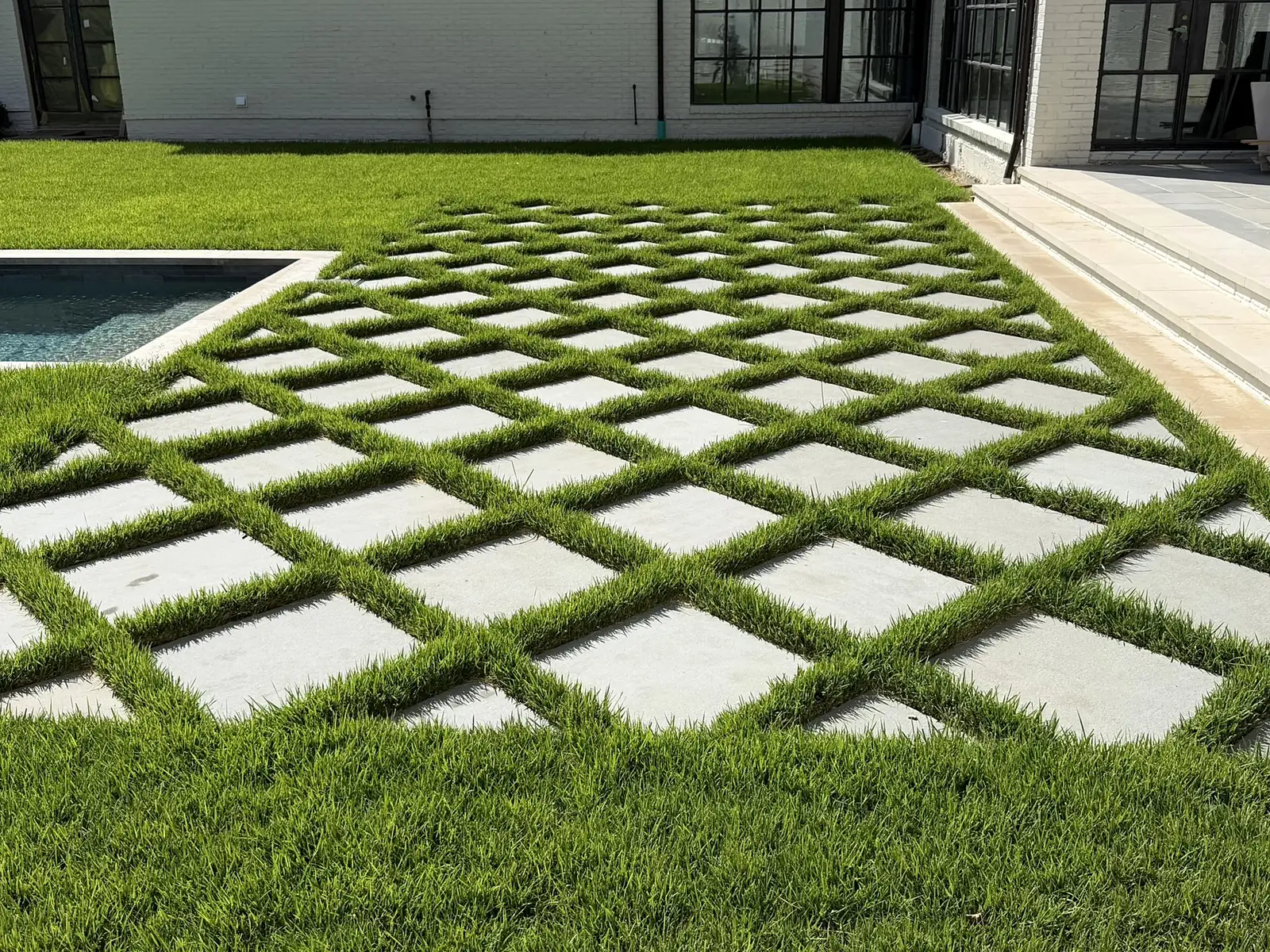 Diamond-set thermal bluestone pavers with grass joints next to cream limestone steps